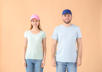 Young couple in stylish caps on color background