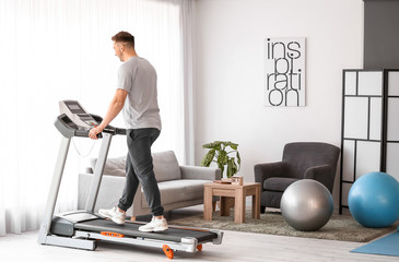 Young man training on treadmill at home