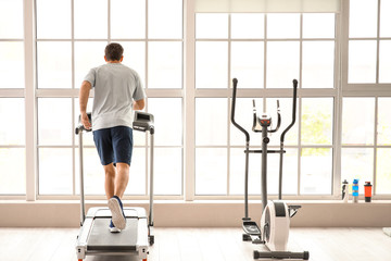 Fototapeta premium Young man training on treadmill in gym