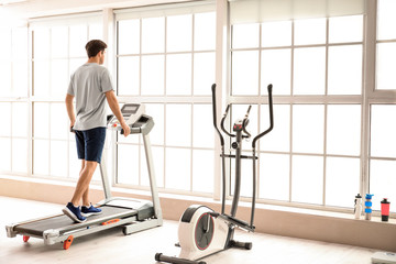 Fototapeta premium Young man training on treadmill in gym