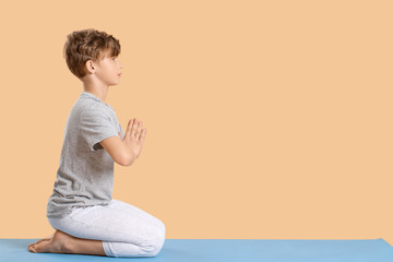 Cute little boy practicing yoga on color background