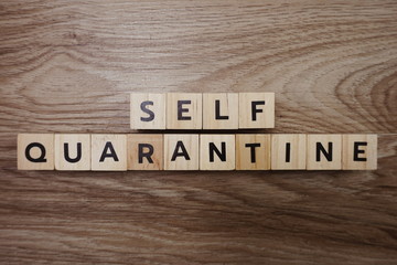 Self-quarantine alphabet letter on wooden background