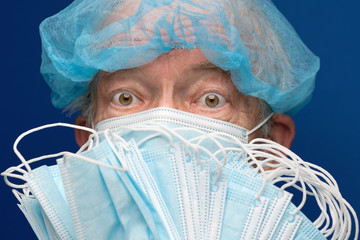Portrait of senior adult fearful glance in medical face mask covering nose, mouth from SARS, 2019-ncov infection. Male additionally covered face many respiratory masks preventing contact with people