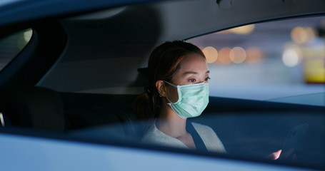 Woman wear medical mask and use of mobile phone sit inside the car