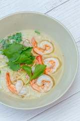 Thai rice soup with shrimp on bowl with white wood background