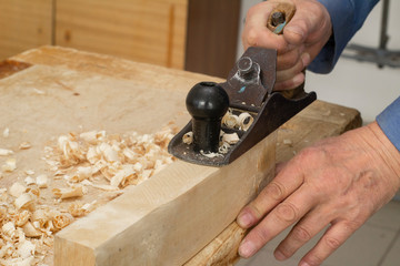 The hand holds the shirt and smooths the surface of the wooden bar. Carpentry workshop.