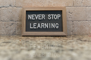 Letter board propped against wall with the words NEVER STOP LEARNING