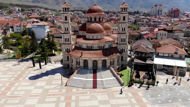 Beautiful orthodox cathedral in Korca town with round red roofs in front of great square paved in tails