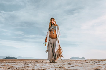 Fototapeta premium beautiful young stylish pregnant woman with boho accessories walking on the beach at sunset