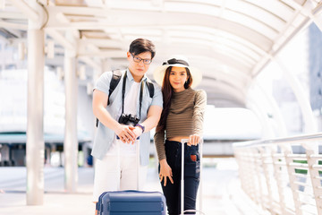 Thai men and women wear casual clothes. They are grabbing the baggage cart and looking at the camera in the concept of tourists who are going to travel on a summer holiday.