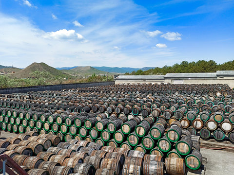 a lot of oak wine casks with madeira wine while maderization on solarium with mountain background. Crimea, Koktebel. Winery.