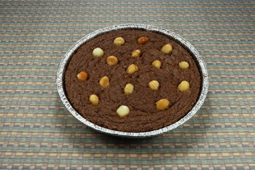 Dark Chocolate cake in Aluminium foil tray. Delicious brownie fudge topping with macadamia nuts. Classic homemade tart and cupcake in Asia. Popular sweet dessert in bakery shop. 