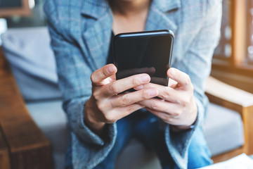 Closeup image of a woman holding and using mobile phone