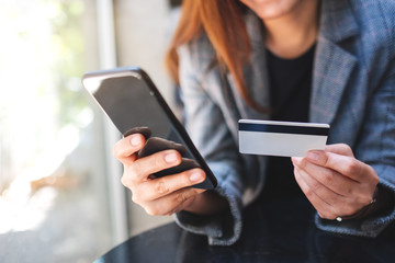 Closeup image of a woman using credit card for purchasing and shopping online on mobile phone