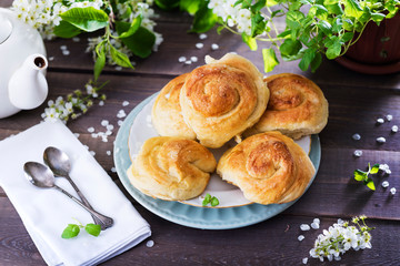 sweet buns on ceramic plate, blossom branches on  wooden background