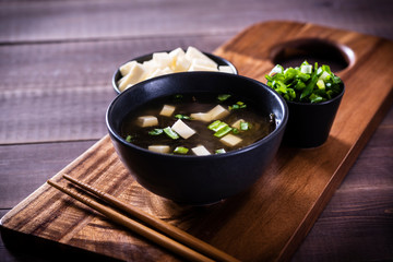 Japanese hot miso soup in a black bowl on the wooden table.