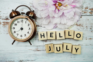 Hello July with alarm clock on wooden background