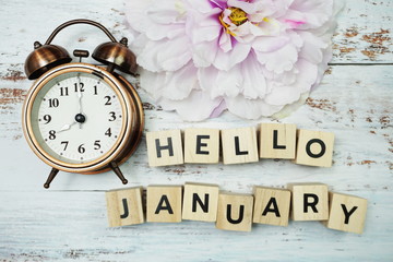 Hello January with alarm clock on wooden background
