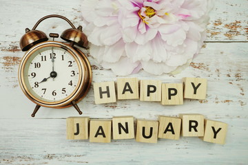 Happy January with alarm clock on wooden background