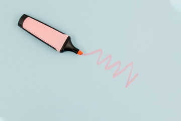 Pink highlighter draws doodle on a blue paper with copy space