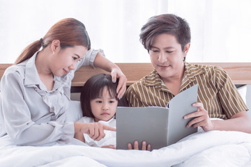 Dad and mom are reading bedtime stories to daughter