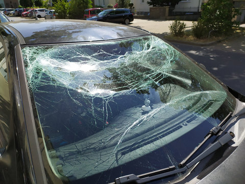 Zersplitterte Windschutzscheibe zeigt kaputte Autoscheibe nach einem Verkehrsunfall mit Fahrerflucht und Polizeieinsatz wegen Trunkenheit am Steuer mit Glasschaden an der Frontscheibe und Splittern