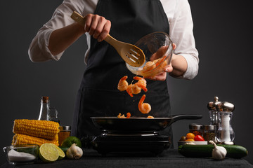 The chef cooks shrimp, seafood, on a background of vegetables. Freezing motion. Thai cuisine, or...