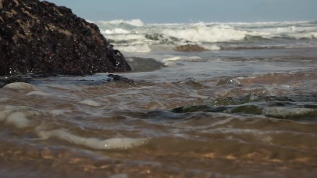Ocean waves crashing onto the beach. Green carpet of moss covering the rocks. Cresmina beach (Praia da Cresmina), Portugal. 