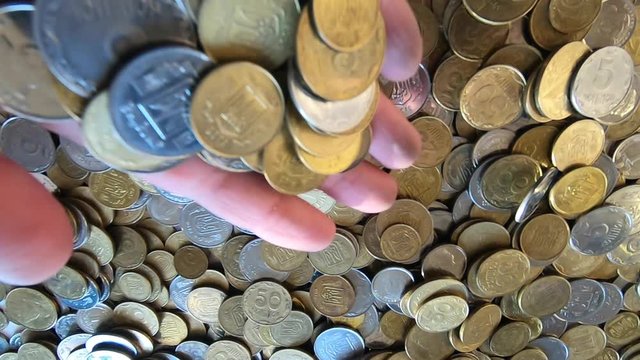 Girl picks up handful of coins in her hand and throws it over coins on table