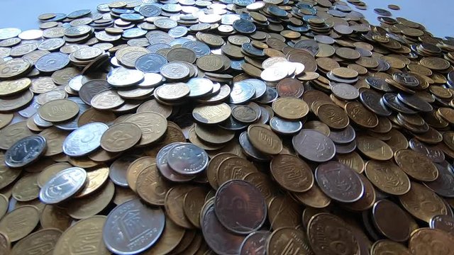 Person picks up handful of coins in hand and throws it over coins on table.