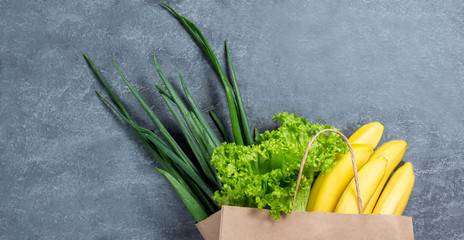 Green vegetables in shopping bag on light stone background