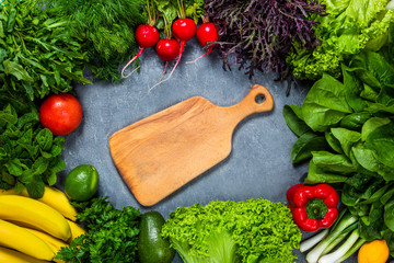 Vegan Menu Concept. Wooden rustic cutting board with ingredients for cooking vegan food on stone background