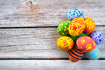 Pile of painted ester eggs in various colors on wooden table. Ester holiday concept. - obrazy, fototapety, plakaty