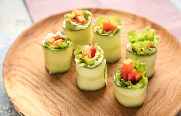 Plate with tasty cucumber rolls on table