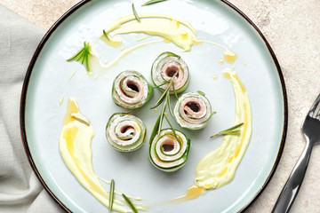 Plate with tasty cucumber rolls on light background