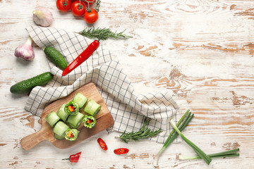 Board with tasty cucumber rolls on table