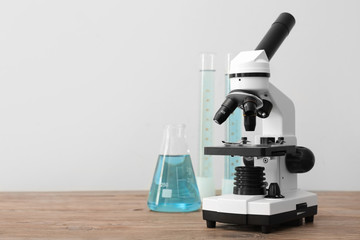 Modern microscope and laboratory glassware on table