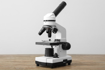Modern microscope on table against light background