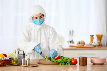 Woman in biohazard suit cooking in kitchen