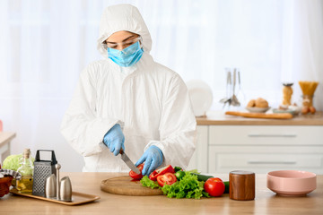 Woman in biohazard suit cooking in kitchen