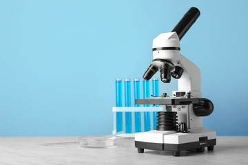 Modern microscope and test tubes on table