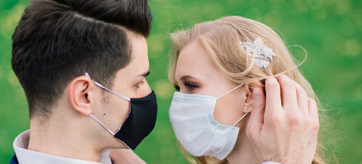 Young loving couple walking in medical masks in the park during quarantine on their wedding day. Coronavirus, disease, protection, sick, illness flu europe celebration canceled.