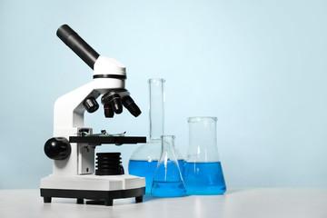 Modern microscope and laboratory glassware on table