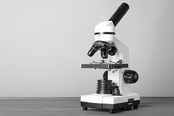 Modern microscope on table against grey background