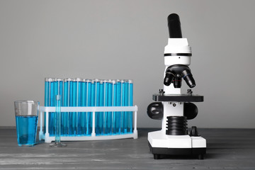 Modern microscope and test tubes on table