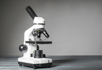 Modern microscope on table against grey background