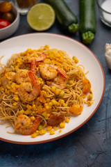 Fried vegetables, seafood shrimp with spaghetti on the background of vegetables and ingredients. On a blue texture