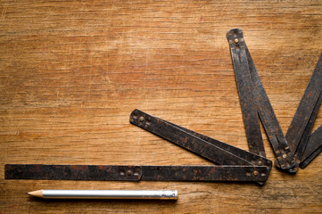 Measuring iron folding meter old, photographed on a shabby wooden surface.