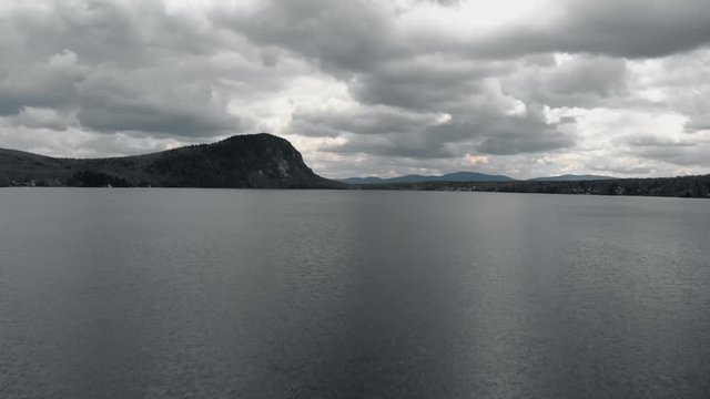 Flying over the beautiful, calm waters by Mount Pinacle in Canada during a cloudy day - low aerial