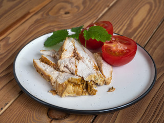 Light appetizer of sliced chicken ham and red tomatoes on a light plate